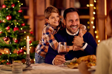 Joyful Father And Son Celebrate Christmas Dinner With Warm Candlelight And Tree Decorations