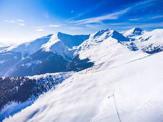 Winter landscape in the Carpathian Mountains, Romania. Snow-covered peaks, frozen forests, and a peaceful mountain valley bathed in soft morning light.