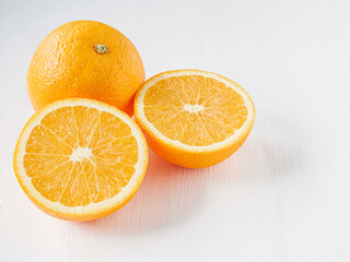Halved orange fruit on white wooden background, close-up