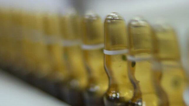 High-definition footage of an automated cleanroom assembly where glass ampoules are washed, filled with injectable medication, sterilized, and hermetically sealed. Showcases precision robotics, strict