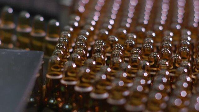 High-definition footage of an automated cleanroom assembly where glass ampoules are washed, filled with injectable medication, sterilized, and hermetically sealed. Showcases precision robotics, strict