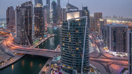 Obraz premium Aerial view of Dubai Marina residential and office skyscrapers with waterfront day to night timelapse