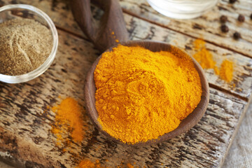 Dry turmeric root powder with ground black pepper in the background