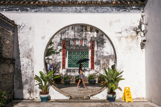 Young woman walking in front of circular opening at Mandarin's house, Macao