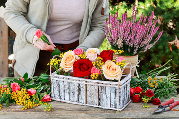 Florist at work: woman shows how to make classic floral arrangement with roses, heather, tansy and...