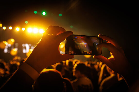 Smartphone capturing live concert in golden light atmosphere - Powered by Adobe