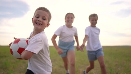 Group of children playing together with a ball. Child summer soccer concept. group of children are running around in a park with a ball. Group of children playing together in fun a park while running.