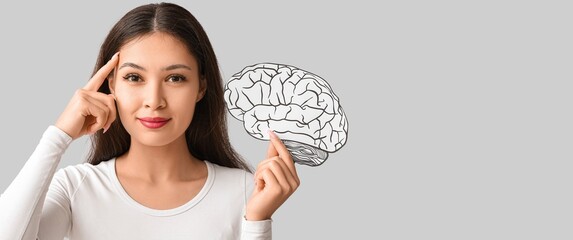 Naklejka premium Young Asian woman holding paper brain on grey background with space for text
