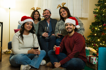 Fototapeta premium Relaxed young adults celebrating christmas party enjoying wine and company