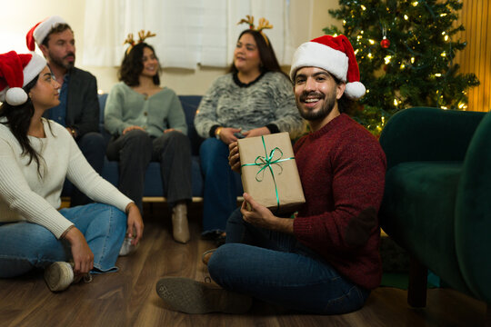Portrait of a Latin man celebrating christmas party exchanging holiday gifts - Powered by Adobe