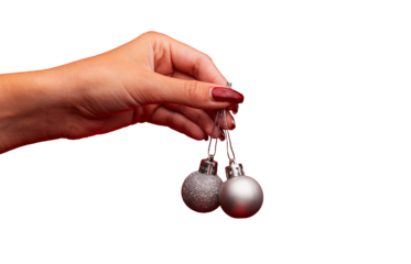 A woman's hand holding two small shiny grey ornament balls. A woman's hand holding Christmas decorations. Christmas ornament balls isolated transparent. Xmas decorations