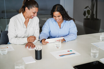 Business women sharing ideas inside company office - Females latin colleagues discussing new financial project - Brainstorming, entrepreneur and corporate concept - Main focus on right girl face