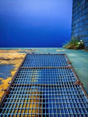 Weathered steel grating on worn concrete ground with rusty metal mesh and faded color