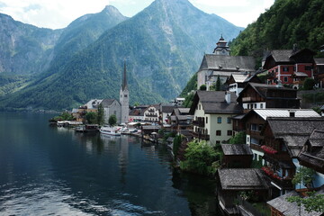 Fototapeta premium Picturesque view of Hallstatt village and church by the lake with alpine mountains, Austria