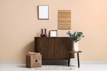 Vase with eucalyptus twigs on table near beige wall in room