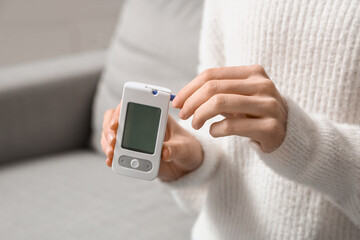 Young diabetic woman with digital glucometer at home