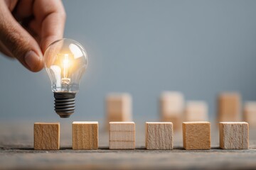 Sparking Innovation with a Real Lightbulb Hand Positioning Bulb on Set of Wooden Blocks Unlocking Potential for Creative Ideas in Business Education Personal Growth Solving Problems