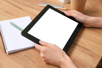 Young woman with modern tablet at wooden table