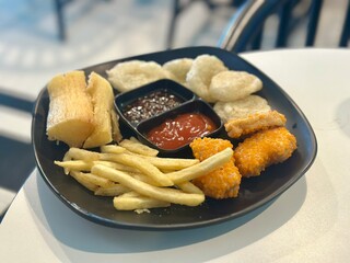Assorted Indonesian fried snacks served on a plate – cassava fries, potatoes, sausages, and nuggets. BSD, Indonesia - October 2025