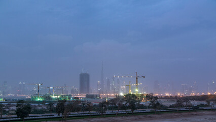 Obraz premium Skyline of construction cranes tower with skyscrapers on background in the Middle East day to night timelapse, Dubai