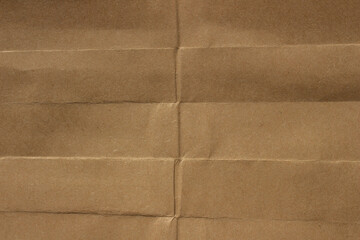 Fototapeta premium Brown crumpled kraft paper texture with deep folds and creases