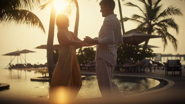 Romantic couple embraces by the tropical pool at golden hour during their luxurious sunset vacation