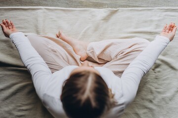 Smiling woman practicing yoga at home, doing seated forward bend on a mat. Healthy lifestyle, flexibility, self care, and balance in a peaceful home environment