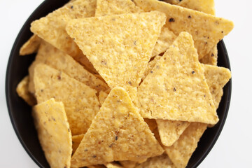 Golden tortilla triangles. Bowl filled with crunchy corn chips under soft light.