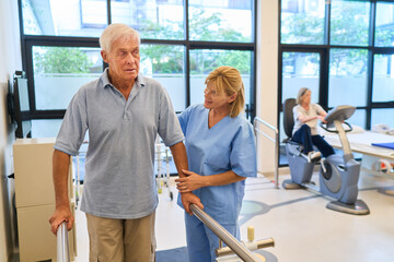 Elderly man assisted by nurse in a rehabilitation center for physical therapy