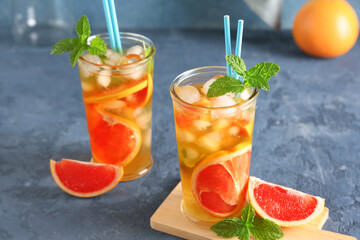 Glasses of cold tea with grapefruit slices and mint leaves on blue grunge background