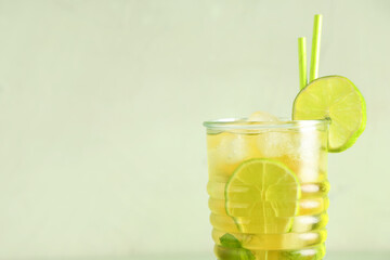 Glass of cold tea with lime slices and mint leaves on green background