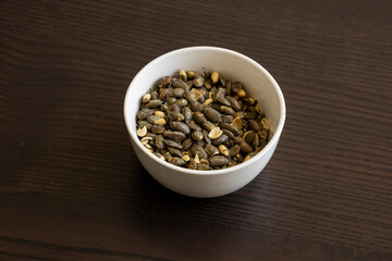 baked pumpkin seeds in small white bowl close up