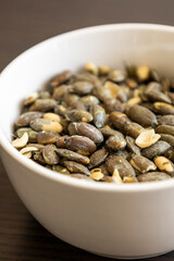 baked pumpkin seeds in small white bowl close up
