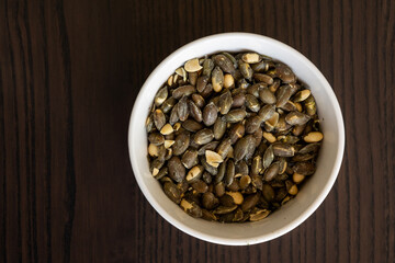 baked pumpkin seeds in small white bowl close up