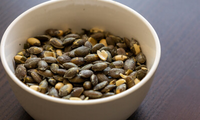 baked pumpkin seeds in small white bowl close up
