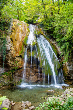 Jum Jum waterfall in the forest on a green background on a bright sunny day. Flora nature plants sights of Russia.