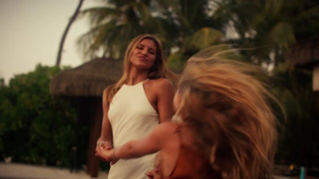 Happy mother and daughter dance playfully enjoying a tropical resort vacation together