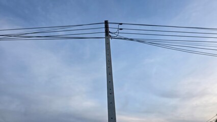 Fototapeta premium Power Lines Against a Blue Sky with Soft Cloud Cover in the Background During Daytime