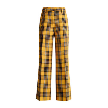 High-waisted, wide-leg trousers feature a bold yellow and black plaid pattern, isolated on black