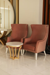 Two elegant pink chairs flank a round white table, creating a welcoming seating area. The modern decor features smooth lines and a bright atmosphere
