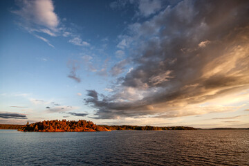A forested island under a cloudy sunset sky