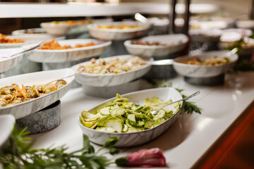 A variety of fresh salads and side dishes are beautifully arranged in marble serving bowls at a buffet. Guests can choose from colorful vegetables and delicious options