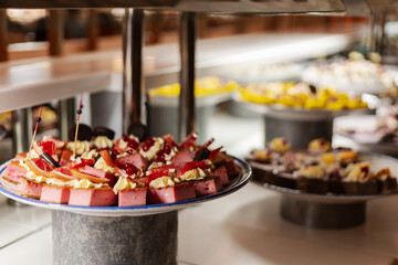 A vibrant assortment of desserts is arranged on a buffet table, featuring layered cakes and colorful pastries topped with fresh fruits and cream, creating an inviting display