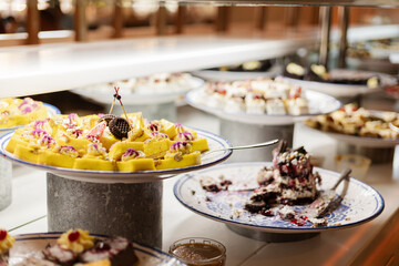 A vibrant dessert buffet features assorted sweets, including cakes and pastries, beautifully arranged on silver platters ready for guests to enjoy at a lively celebration