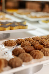 A variety of sweet treats are neatly presented on a silver tray at a dessert display. These include round and shaped confections, showcasing diverse textures and flavors
