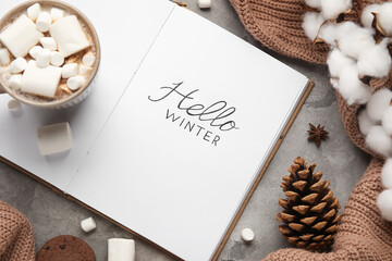 Notebook with text HELLO WINTER, cocoa, cotton flowers and sweater on grunge background, closeup