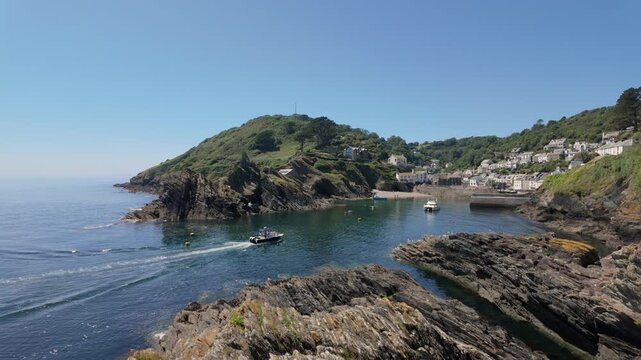 Fisherman in a fishing boat sails into Polperro bay in Cornwall, UK. Near looe. Beautiful picturesque water, and iconic rock formation. 