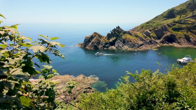 A small fishing boat leaves Polperro bay in Cornwall in the sunshine. Polperro is an unspoilt fishing village on the south coast of Cornwall. 