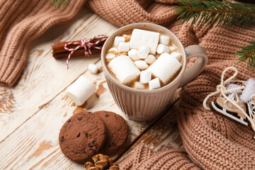 Cup of cocoa with marshmallows, cookies and sweater on white wooden background. Hello winter