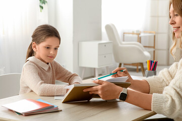 Little girl with book and tutor studying at home
